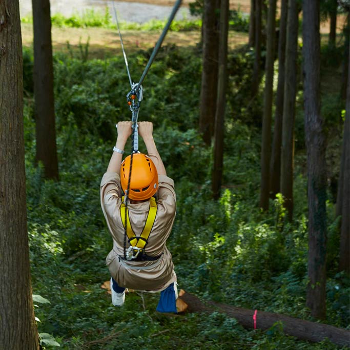 ハーネスを着用し森のジップラインを滑る子ども/農園リゾート ザファーム(千葉県/香取市)