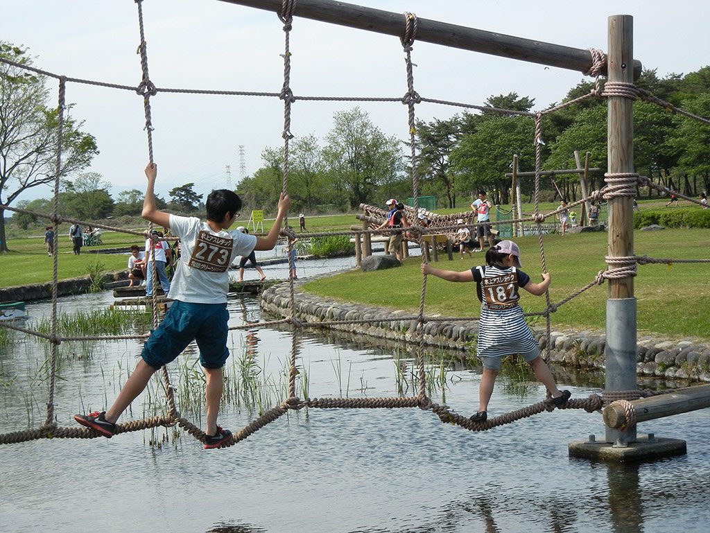 水上のネットを進む子どもたち／鬼怒グリーンパーク水上アスレチック（栃木県／高根沢町）