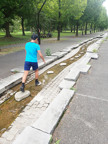 せせらぎの石の上を渡り歩く子ども／舎人公園（東京都/足立区）