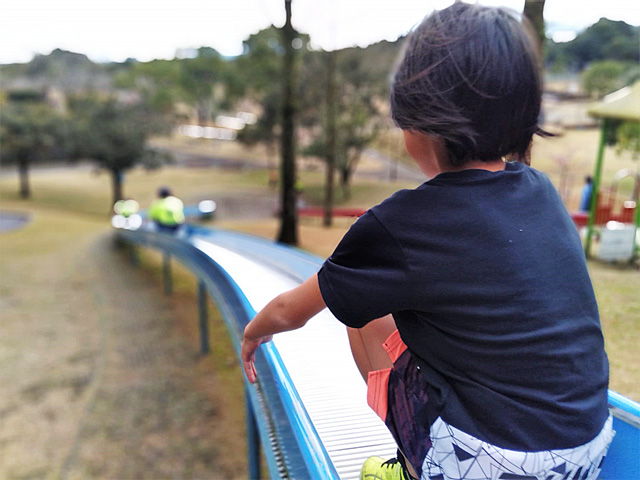 青いローラー滑り台を滑る子ども/久峰総合公園(宮崎県/宮崎市)