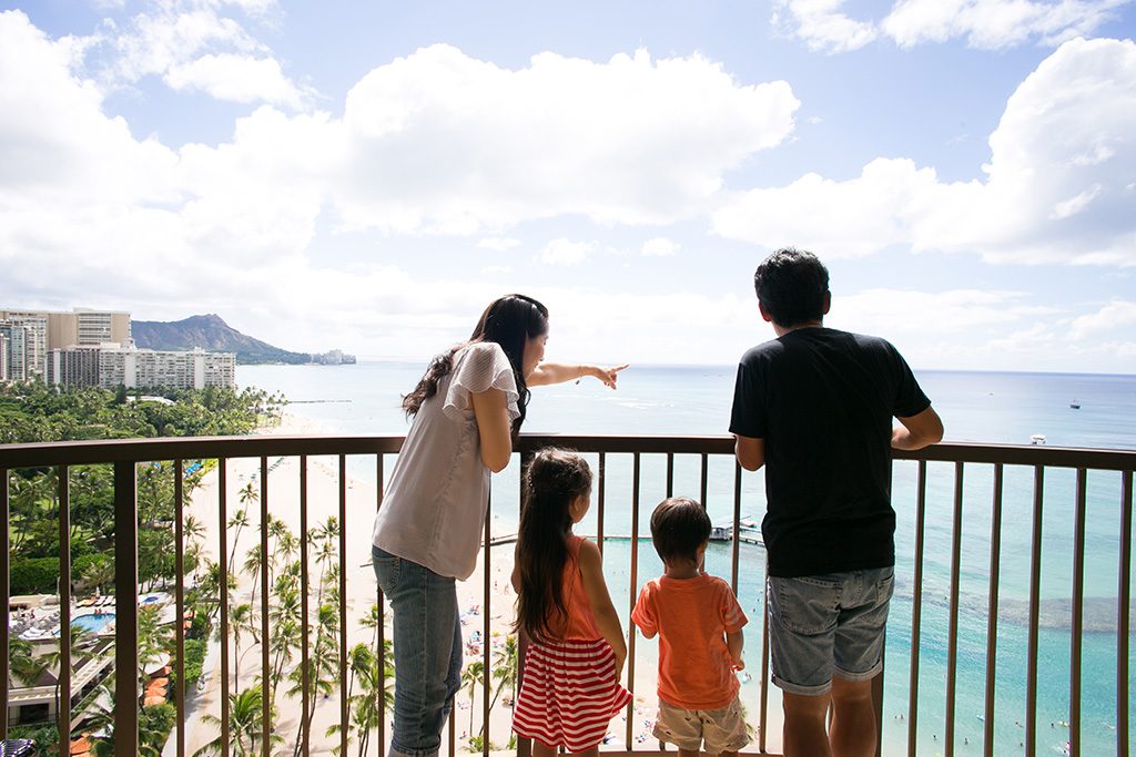 ホテルのテラスから海を眺める家族（ハワイ）