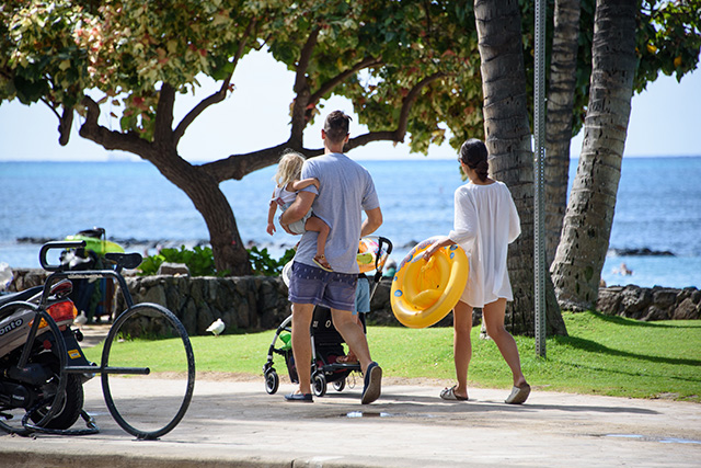 ハワイのビーチ沿いの公園を歩く親子