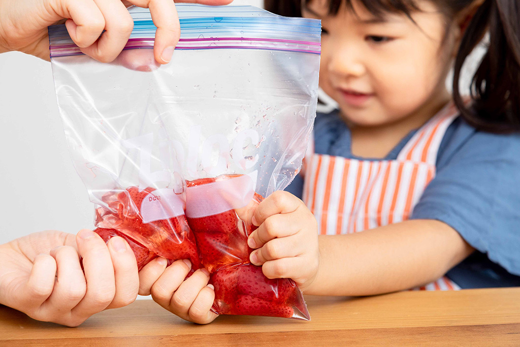保存袋のいちごをモミモミする子ども