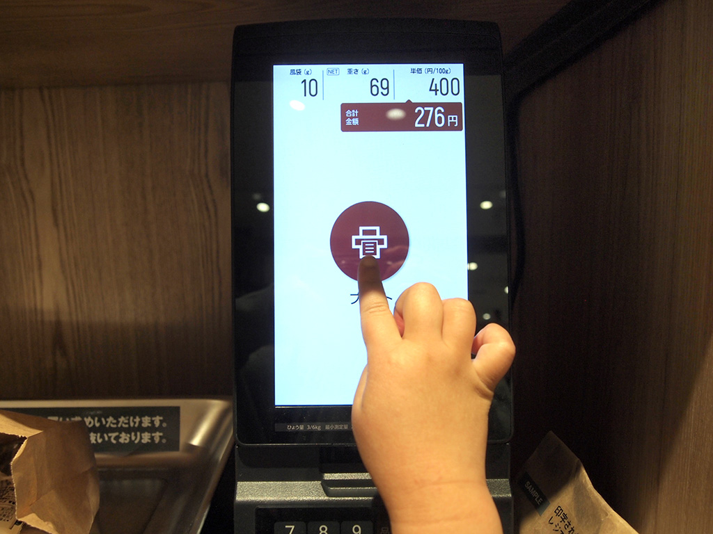 金額のシールを出力する様子/無印良品「お菓子の量り売り」