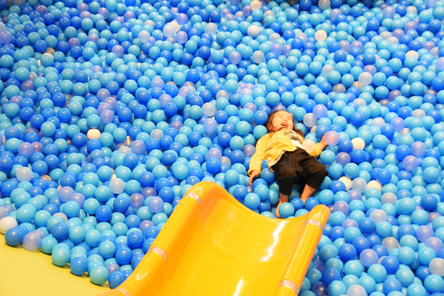 「アドベンチャーオーシャン」ボールプールのすべり台をすべって満面の笑顔のキッズ/東京ドームシティ「アソボ~ノ!」(東京都/文京区)