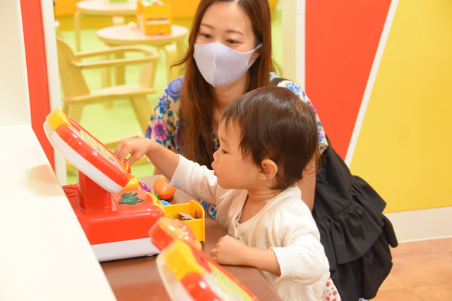 街のエリア「カラフルタウン」のレジのおもちゃに夢中の小さいキッズ/東京ドームシティ「アソボ~ノ!」(東京都/文京区)