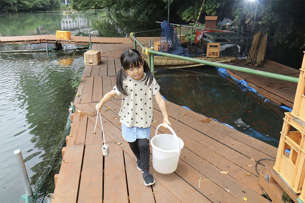 釣り堀体験でバケツを運ぶ子ども