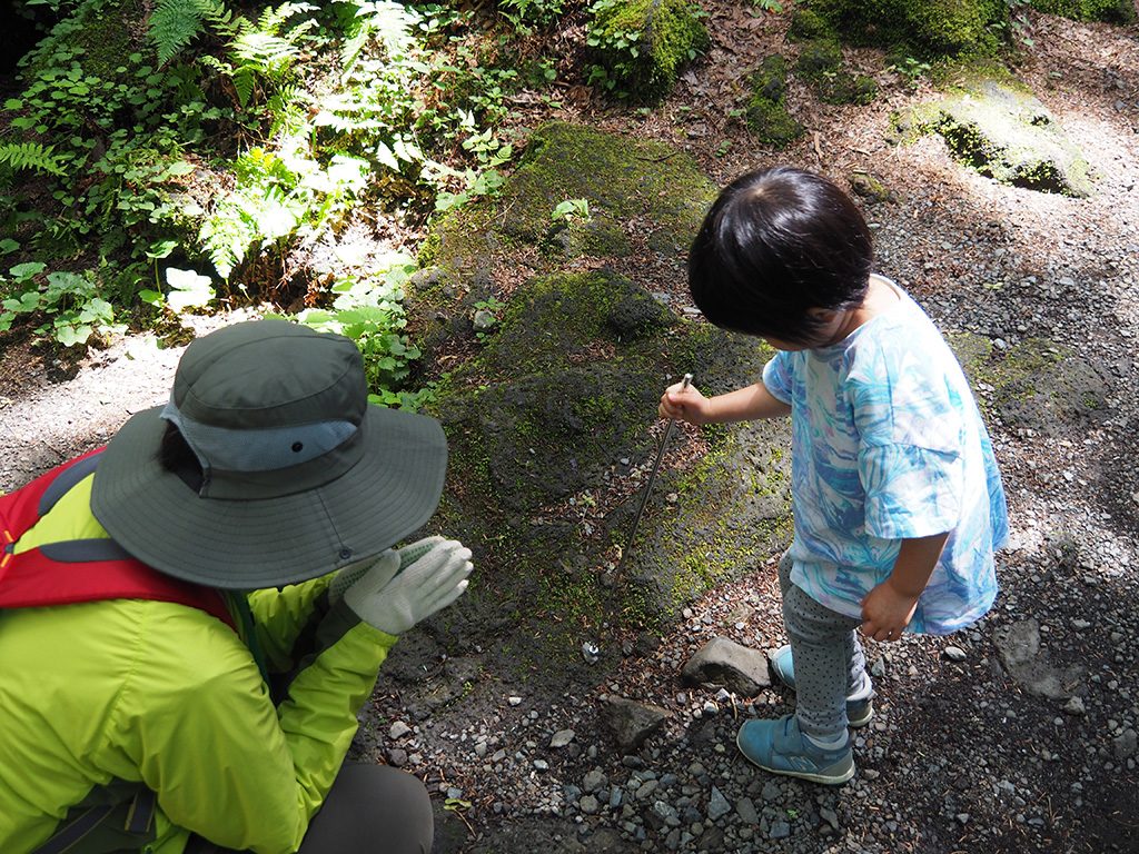 先に磁石がついた棒で石にふれる様子/洞窟「富岳風穴」（山梨県/富士河口湖町）