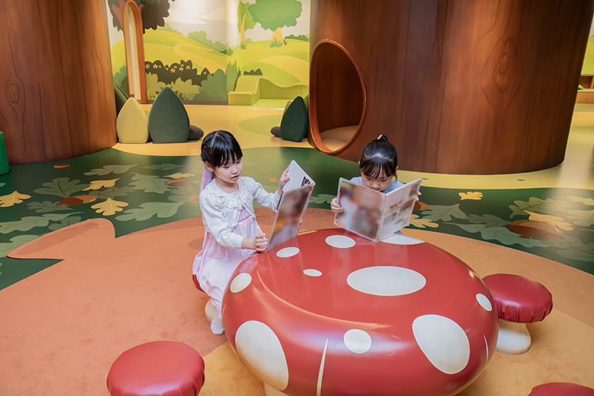 キノコのテーブルで絵本を読む子どもたち/チップとデールのプレイグラウンド
