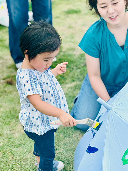 絵の具を使って、無地の傘にペイントする様子/アート in 青山パーク　～空の下で傘にアートしよう～（東京都/港区）
