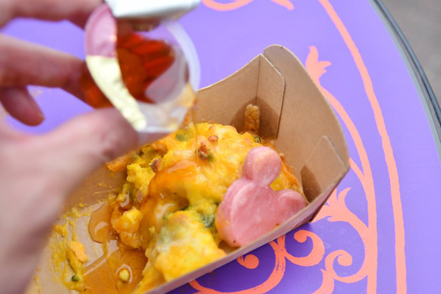 カボチャのニョッキグラタンにメープルシロップをかける様子/東京ディズニーシー(千葉県/浦安市)