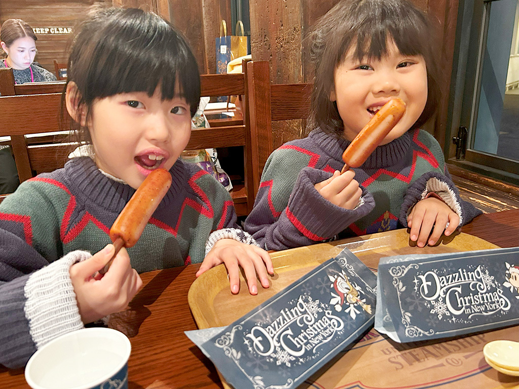 レストラン「ドッグサイドダイナー」で骨付きソーセージを食べる様子│2024クリスマス/東京ディズニーシー(千葉県/舞浜市)