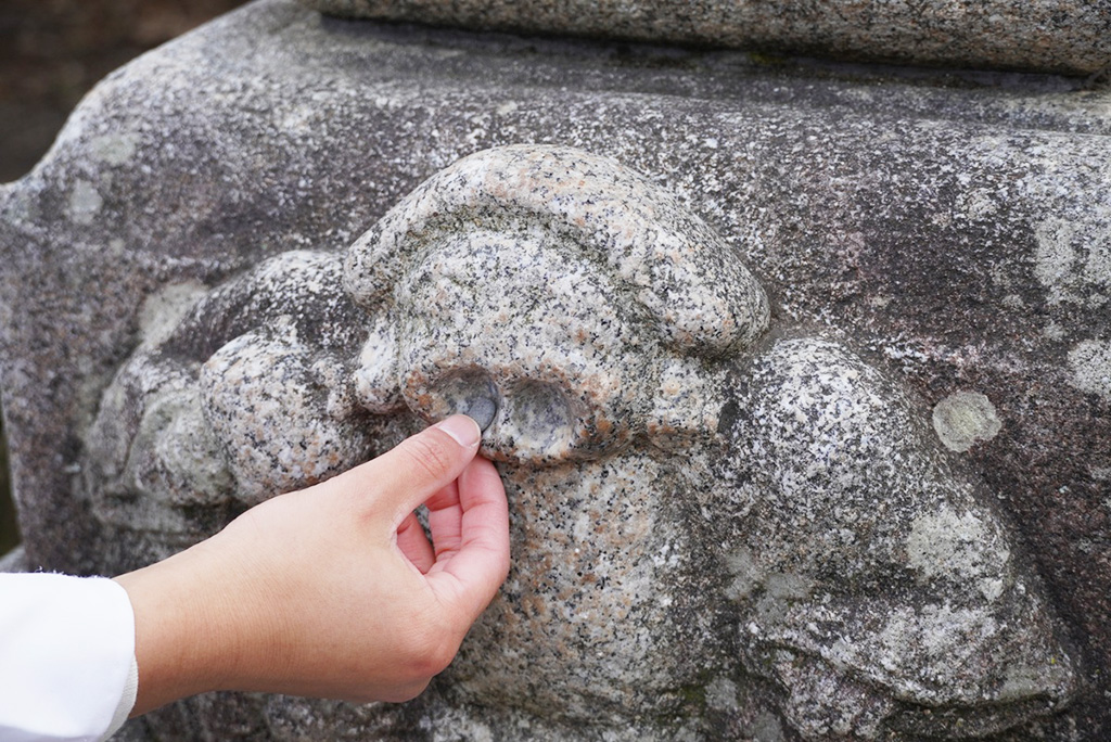 大黒様の穴に小石をのせる様子/北野天満宮（京都府/京都市）