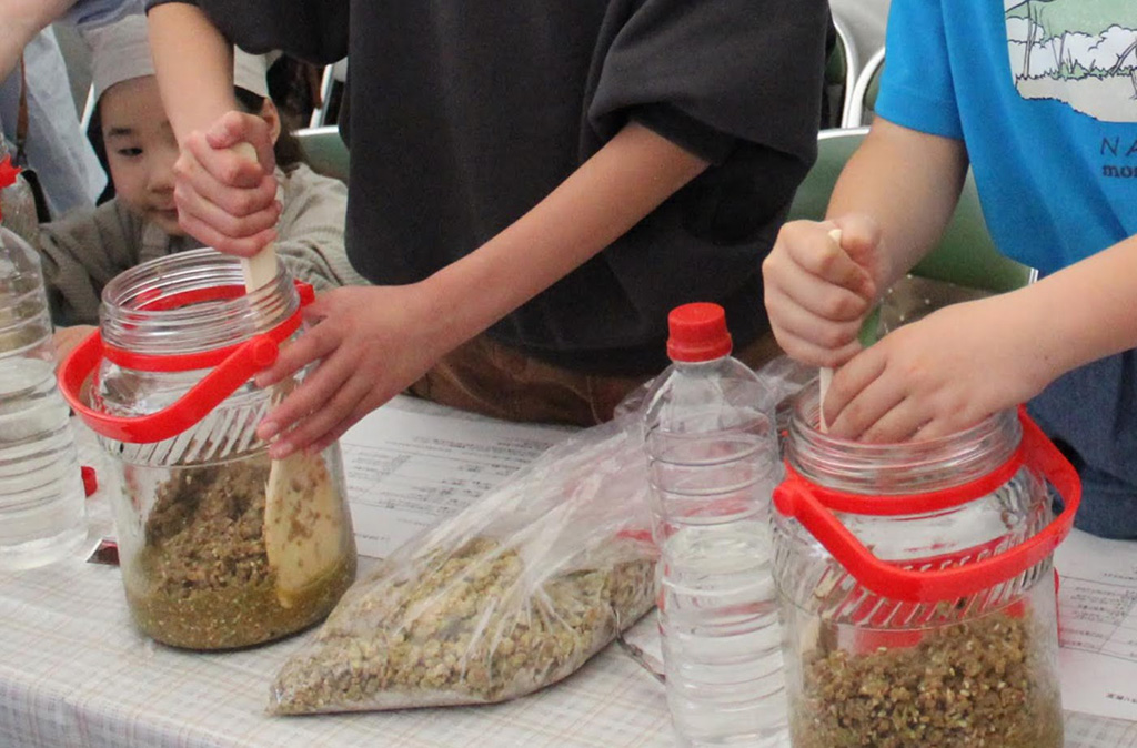 「麹」と「塩水」を木べらでかき混ぜる様子